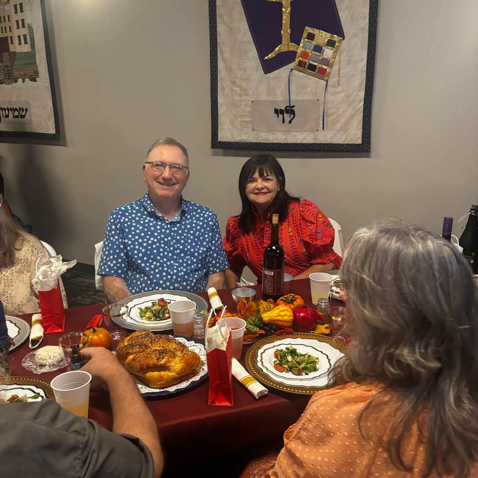 Guests smiling around a table set with challah