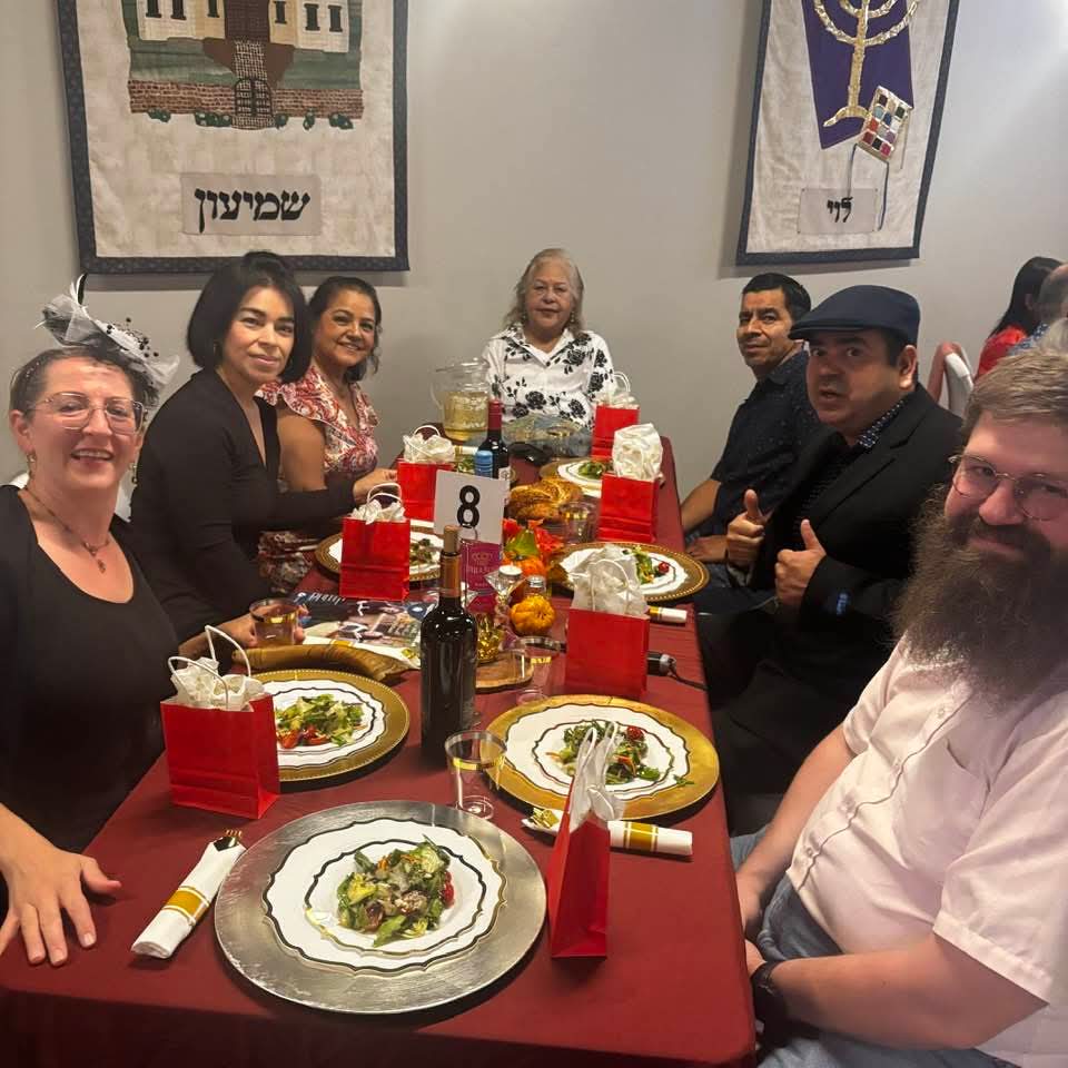A long table of guests beneath the tribal banners